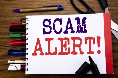 Scam Uyarısı gösteren el yazısı duyuru metin. İş kavramı dolandırıcılık uyarı yazılı üstünde defter, kalem gibi Ofis donanımı ile ahşap arka plan için renkli marker makas  