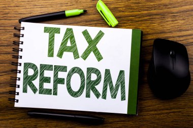 El yazısı duyuru metni vergi reformu gösteriliyor. Hükümet değişikliği defter kitap bir not kağıdına ahşap arka plan üzerinde yazılı vergi için iş kavramı. Yeşil word mektup. Fare için ileri.