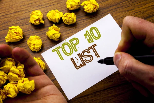 Λέξη, γράφοντας Top 10 κατάλογο των δέκα. Αντίληψη για επιτυχία δέκα κατάλογο γραμμένο στο χαρτί ενός διαγραμμισμένου σημειωματάριου ΣΗΜΕΙΩΣΗ σε ξύλινο υπόβαθρο με διπλωμένο χαρτί έννοια σκέψης για την ιδέα. Χέρι άνδρα και δείκτη. — Φωτογραφία Αρχείου