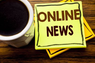 Online haber gösteren el yazısı metin. Ahşap ahşap arka plan kahve fincanı ile yapışkan not kağıdına yazılı Online gazete makalesi için iş kavramı