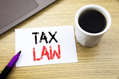 Vergi Hukuku gösteren el yazısı duyuru metin. Vergilendirme Vergi defter kitap dizüstü kahve ile ofiste ahşap arka plan üzerinde yazılı kural için iş kavramı