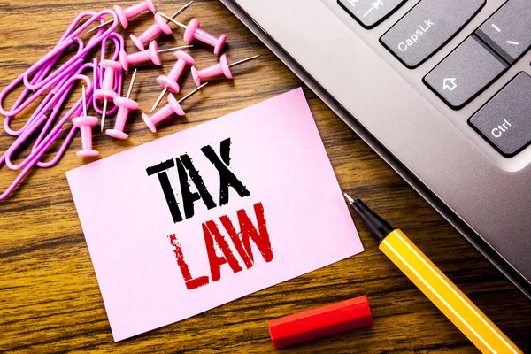 手書きの文字は、税法を示します。キーボードの横に木製の背景のピンクの付箋紙に書かれた課税税規則のビジネス コンセプトです。赤ペンで. — ストック写真