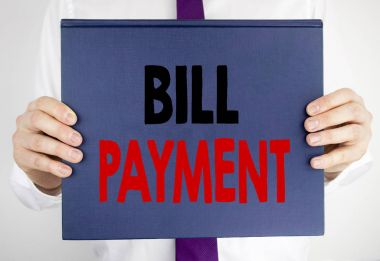 Fatura ödeme gösterilen metin yazma. Fatura ödeme tarafından adam bulanık takım elbise arka planda tutarak kitap defter kağıt üzerinde yazılı masrafları için iş kavramı.