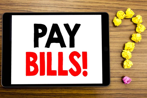 Writing text showing Pay Bills. Business concept for Finance Paying Online written on tablet computer on the wooden background with question mark made of folded paper.