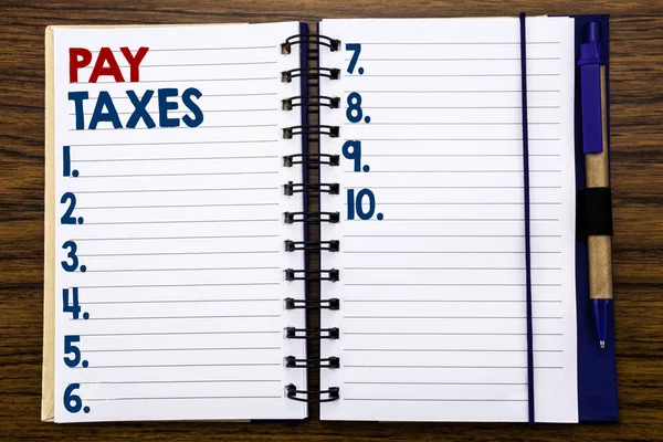 Escrevendo texto mostrando Pay Taxes. Conceito de negócio para tributação sobre a devolução Escrito em papel de nota de caderno, fundo de madeira com caneta e marcador . — Fotografia de Stock
