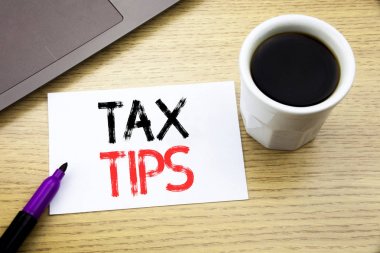 Vergi ipuçları gösteren el yazısı duyuru metin. İpucu eşzamanla defter kitap dizüstü kahve ile ofiste ahşap arka plan üzerinde yazılı vergi için iş kavramı