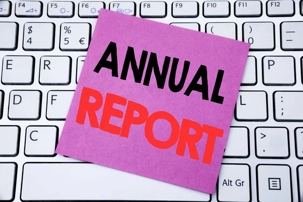 Χειρόγραφου κειμένου ανακοίνωση παρουσιάζει την ετήσια έκθεση. Επιχειρηματική ιδέα για ανάλυση επιδόσεων γραμμένο σε χαρτί κολλώδη σημείωση στο πληκτρολόγιο λευκό φόντο. — Φωτογραφία Αρχείου
