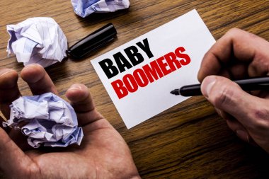 El yazısı metin Bebek Boomers. Demografik defter bir not kağıdına katlanmış kağıt anlam düşünce fikir için ile ahşap arka plan üzerinde yazılı üretimi için kavram. Adam el ve marker.