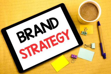 Kavramsal el marka stratejisi gösterilen metin resim yazısı yazma. Pazarlama fikir planı yazılmış tablet laptop, yapışkan not, kahve ve kalem ile ahşap arka plan için iş kavramı