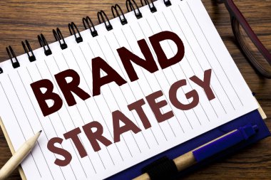 Marka stratejisi gösterilen metin resim yazısı ilham yazma el. Defter not kağıdı, gözlük kalem ve marker ile ahşap arka plan üzerinde pazarlama fikir yazılmış planı için iş kavramı.