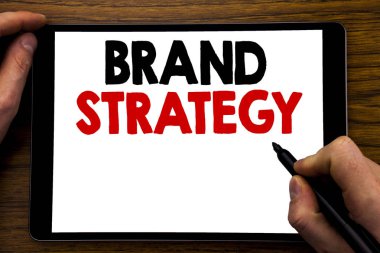 Marka stratejisi gösteren el yazısı duyuru metin. Pazarlama fikir planı yazılmış tablet laptop, işadamı el, parmak PC'de yazma ile ahşap arka plan için iş kavramı.