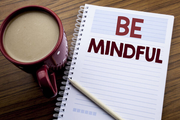 Hand writing text caption inspiration showing Be Mindful. Business concept for Mindfulness Healthy Spirit written on note paper notepad book on the wooden background with coffee and pen.
