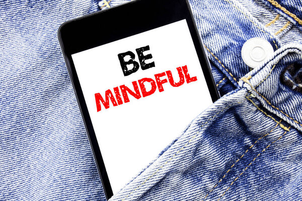Hand writing text caption inspiration showing Be Mindful. Business concept for Mindfulness Healthy Spirit Written phone mobile phone, cellphone placed in the man front jeans pocket.