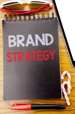 Word, marka stratejisi yazma. Defter kitap, yapışkan güneş gözlüğü ve kırmızı kalem ile ahşap arka plan üzerinde pazarlama fikir yazılmış planı için iş kavramı