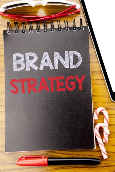 Word, writing Brand Strategy. Business concept for Marketing Idea Plan Written on the notebook book, wooden background with sticky sunglasses and red pen