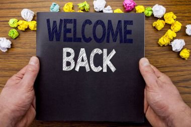 Word, hoş geldiniz geri yazma. Not defteri defter kitap adam işadamı el ve parmak ile ahşap ahşap arka plan üzerinde yazılı duygu tebrik için iş kavramı.