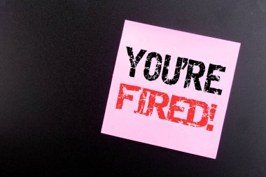 Word, writing You Are Fired. Business concept for Unemployed or Discharge written on sticky note, black background with copy space clipart