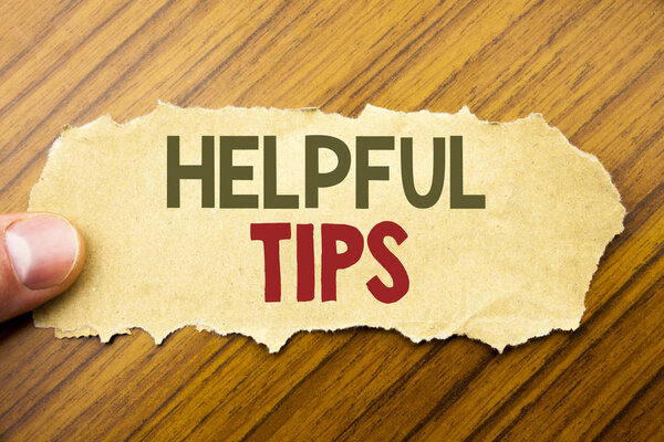 Writing text showing Helpful Tips. Business concept for Help in FAQ or Advice, written on note paper on the wooden background with human finger. Vintage style.