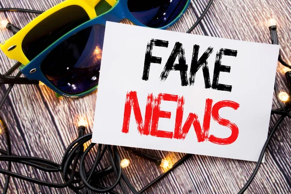 Tekst intoetsen met Fake Nieuws. Businessconcept voor Hoax journalistiek geschreven notitie met kopie ruimte op oude hout houten achtergrond met zonnebril — Stockfoto