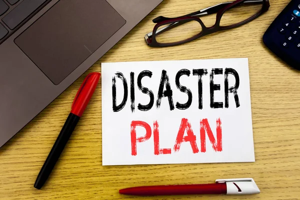 Conceptual hand writing text showing Disaster Plan. Business concept for Emergency Recovery written on paper, wooden background in office with copy space, marker pen and glasses