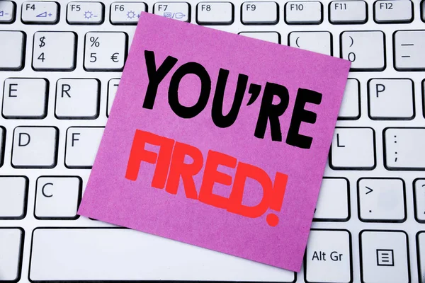 Escrita à mão Texto de anúncio mostrando que você está demitido. Conceito de negócio para desempregado ou descarga escrita em papel de nota pegajosa no fundo do teclado branco . — Fotografia de Stock