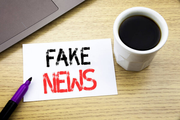Handwriting Announcement text showing Fake News. Business concept for Hoax Journalism written on notebook book on the wooden background in the Office with laptop coffee