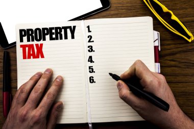 Word, emlak vergisi yazma. Emlak gelir vergilendirme yazılı kitap, işadamı el üstünde belgili tanımlık defter yazma parmak ile ahşap arka plan için iş kavramı.