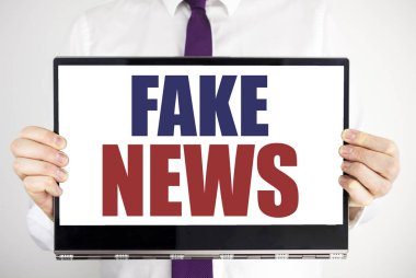Word, sahte haber yazma. Hoax gazetecilik yazılı için iş kavramı tablet laptop adam tarafından holding arka plan bulanık. Bilgisayarı tutarak işadamı parmak.