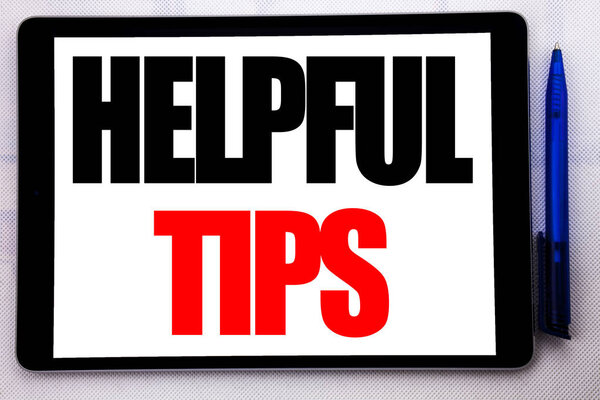 Conceptual hand writing text caption inspiration showing Helpful Tips. Business concept for Help in FAQ or Advice, written on tablet computer on the white background with pen in the office.