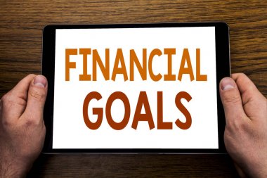 Metin resim yazısı mali hedefleri yazma el. İş kavramı gelir para planı yazılı tablet laptop, işadamı el Pc tutan parmak ile ahşap arka plan için.