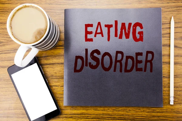 Handwriting Announcement text showing Eating Disorder. Business concept for Medical Problem Written on notepad note paper, wooden wood background with coffee pen and cellphone phone — Stock Photo, Image