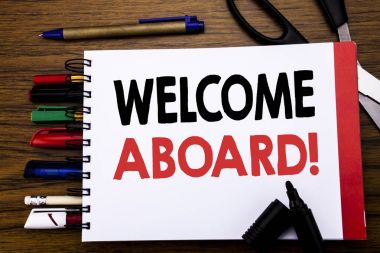 Handwritten text showing Welcome Aboard. Business concept for Greeting Join Member Written on notebook, wooden background with office equipment like pens scissors colourful marker   clipart