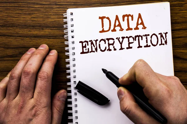 Handwritten text showing word Data Encryption. Business concept for Information Security Written on tablet laptop, wooden background with businessman hand, finger writing on notebook book.