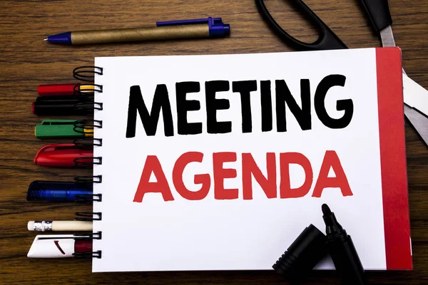 Handwritten text showing Meeting Agenda. Business concept for Business Schedule Plan Written on notebook, wooden background with office equipment like pens scissors colourful marker — Stock Photo, Image