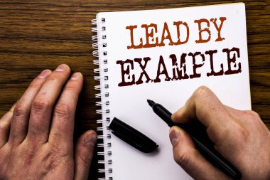 El yazısı metin kelime örnekle yol gösteren. İş kavramı motivasyon ilham yazılı tablet laptop, işadamı el, parmak defter kitap yazma ile ahşap arka plan için.