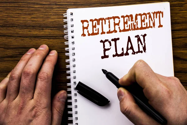 Handwritten text showing word Retirement Plan. Business concept for Pension Finance Written on tablet laptop, wooden background with businessman hand, finger writing on notebook book.