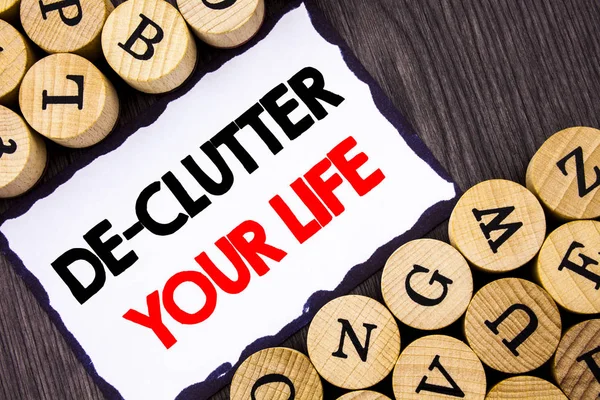Handwritten text sign showing De-Clutter Your Life. Business concept for Free Less Chaos Fresh Clean Routine written on White Sticky Note on the wooden background with letters. — Stock Photo, Image