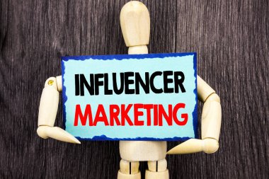 Influancer pazarlama gösterilen metin yazma. Sosyal Medya Online etkisi yapışkan not Holding tarafından heykel üzerinde ahşap arka plan üzerinde yazılı stratejisi anlam kavramı.