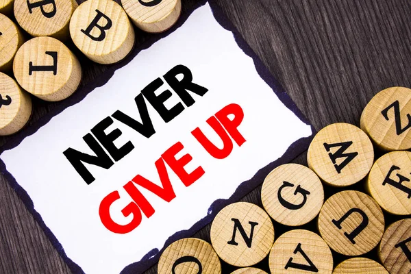 Handwritten text sign showing Never Give Up. Business concept for Motivation Quote For Success Achievement Challenge written on White Sticky Note on the wooden background with letters. — Stock Photo, Image