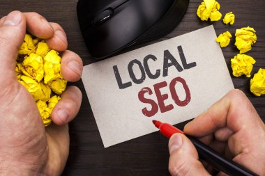 Yerel Seo gösterilen not yazma. Arama Motoru Optimizasyonu stratejisi Optimize yerel adam tarafından not kağıdı tutan işaretçisi üzerinde ahşap arka plan fare üzerinde yazılı anahtar kelimeleri bul vitrine iş fotoğraf.