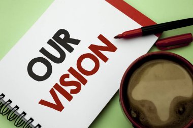 Bizim vizyon yazma el yazısı metin. Yenilik stratejisi görev hedef planı rüya amaç defter kitap düz arka plan kahve fincanı yanındaki yazılı yön anlam kavramı.