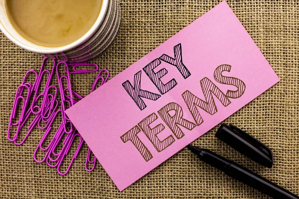 Handwriting text writing Key Terms. Concept meaning Key Plan Strategy Performance Vision Goal Policy Concept Firm written on Pink Sticky Note Paper on the jute background Coffee Cup Pen Pins.