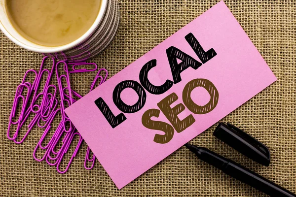 Tulisan tangan teks Lokal Seo. Konsep yang berarti Search Engine Optimization Strategy Optimize Local Find Keywords ditulis di Pink Sticky Note Paper pada jute background Coffee Cup Pen Pins . — Stok Foto