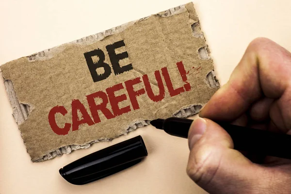 Writing note showing  Be Careful. Business photo showcasing Caution Warning Attention Notice Care Beware Safety Security written by Man Holding Marker on tear Cardboard Piece Plain Background.