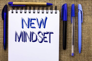 Yeni zihniyet gösterilen not yazma. Tutum son kavramı vizyon davranış planı defter kitap jüt arka plan üzerinde yazılı düşünme vitrine iş fotoğraf yanında kalemler.