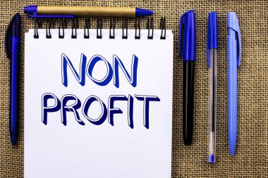 Kar amacı gütmeyen gösterilen not yazma. Hayırsever Wrothless hayırseverlik yardım Unlucrative defter kitap jüt üzerinde yazılı Profitless vitrine iş fotoğraf kalemler yanında arka plan.