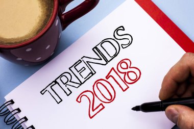 Eğilimleri 2018 gösterilen not yazma. Geçerli hareketi en son Modern marka yeni konsept dizüstü kitap Holding kalem üzerinde düz arka plan kahve fincanı yazılı tahmin vitrine iş fotoğraf.