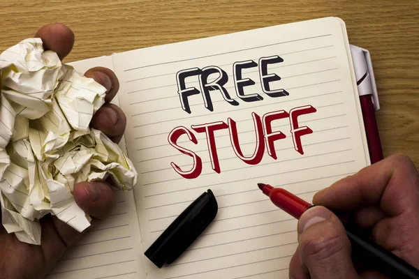 Handwriting text Free Stuff. Concept meaning Complementary Free of Cost Chargeless Gratis Costless Unpaid written by Man on Notebook Book Holding Marker on the wooden background Pen next to it.