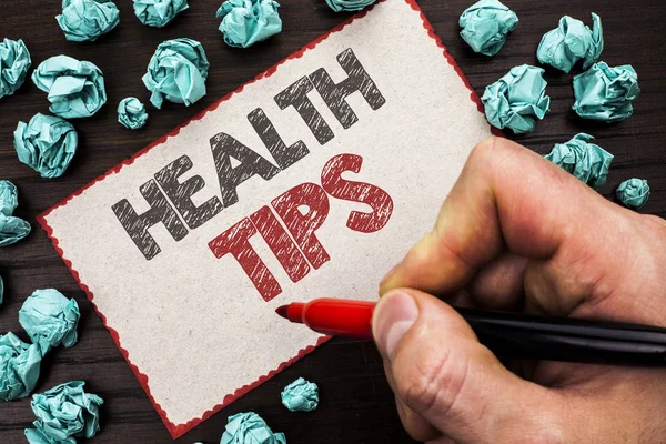 Text sign showing Health Tips. Conceptual photo Healthy Suggestions Suggest Information Guidance Tip Idea written by Man Holding Marker on Cardboard Piece on the wooden background.