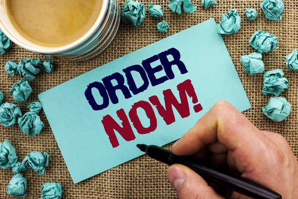 Writing note showing  Order Now. Business photo showcasing Buy Purchase Order Deal Sale Promotion Shop Product Register written by Man Holding Pen on Sticky Note Paper the jute background Cup